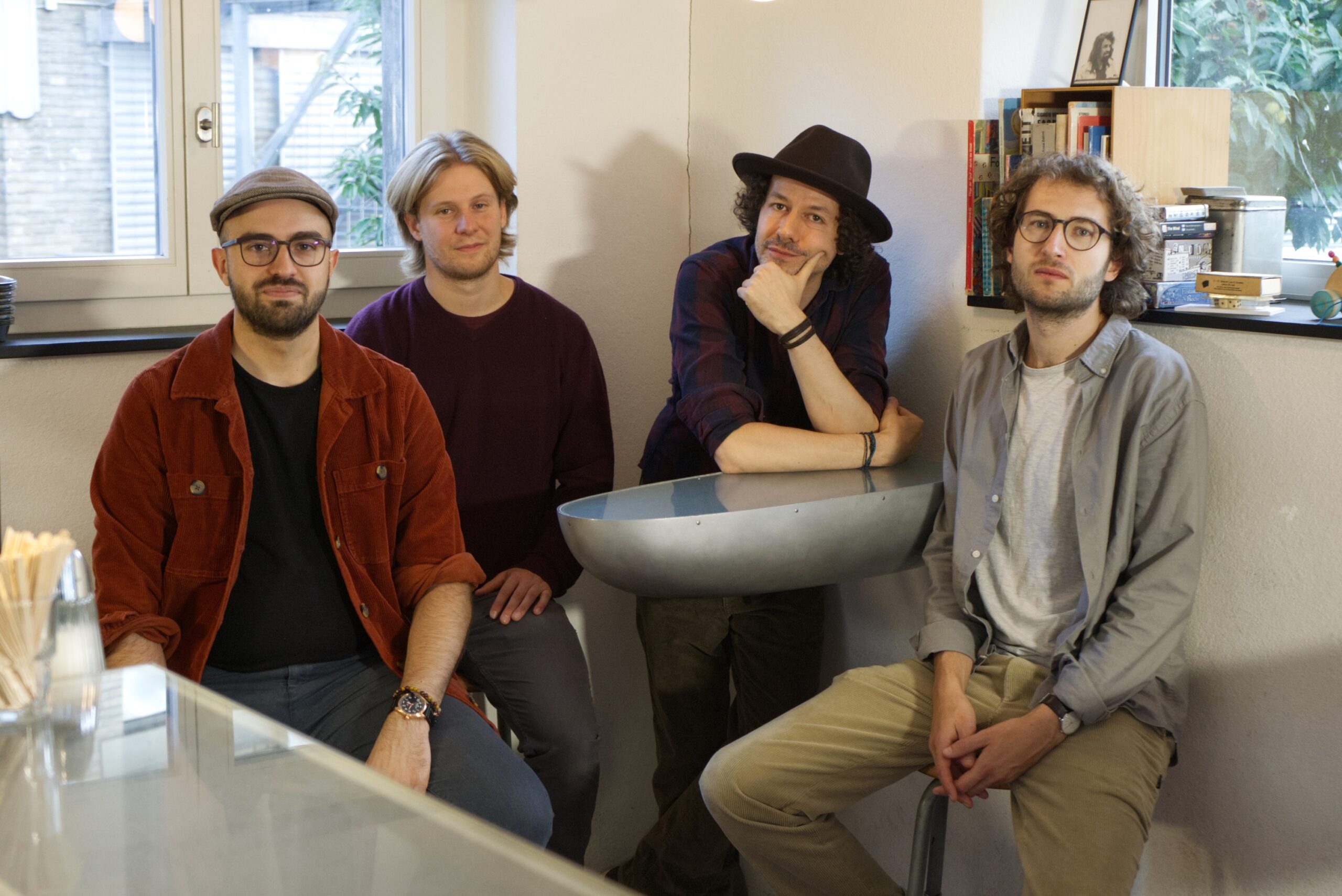 Die Mitglieder der Band Kühnrad Lohse sitzen und stehen um einen Tisch in der Bar Portier in Winterthur.